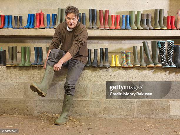 farmer putting on wellington boots - pair stock photos et images de collection