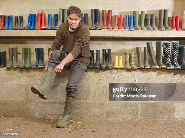 farmer putting on wellington boots - paio foto e immagini stock