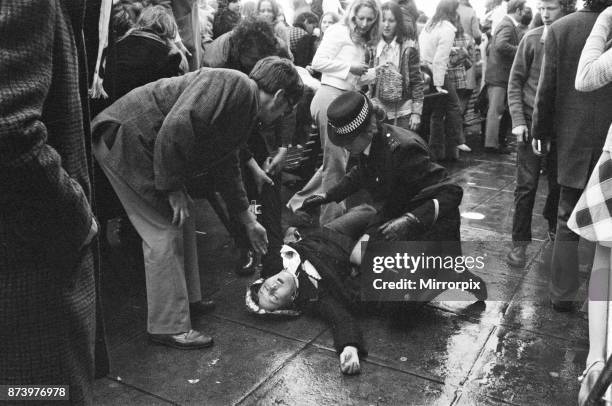 Distraught and in need of medical help, a British fan falls to the ground after seeing her idol David Cassidy leave Heathrow airport after his sell...