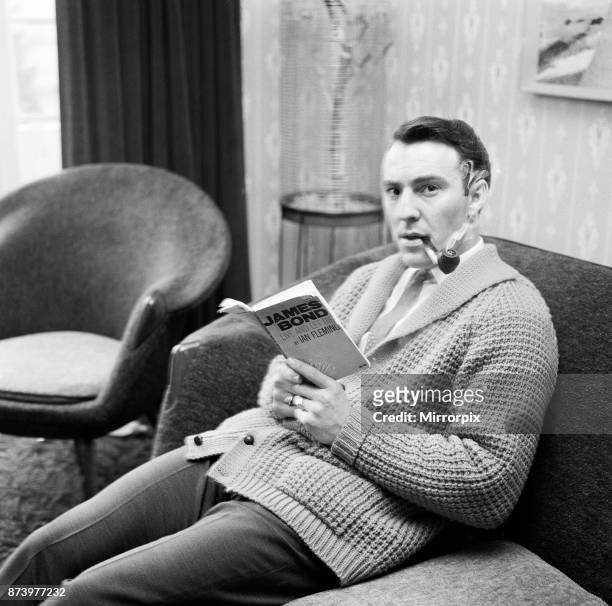 Tottenham Hotspur and England footballer Jimmy Greaves pictured smoking a pipe and reading a James Bond novel at his home in Upminster, Essex, 3rd...