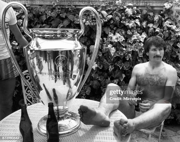 Liverpool footballer Tonny Smith enjoys a bottle of beer as he sits with the famous European Cup trophy following his side's historic victory over...