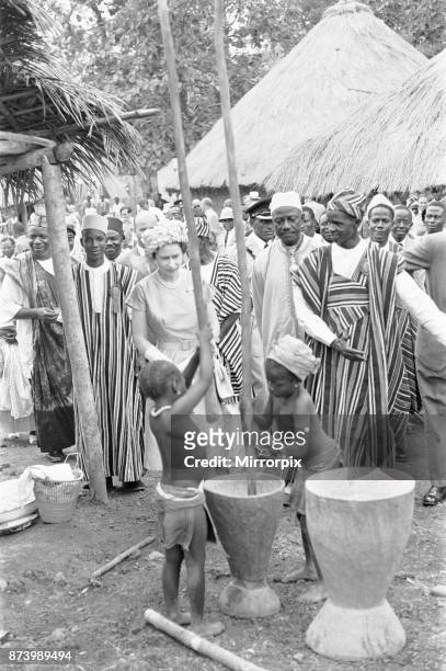 Queen Elizabeth watches two children grinding corn during a visit to Hangha in Kenema, an eastern province of Sierra Leone 1st December 1961.