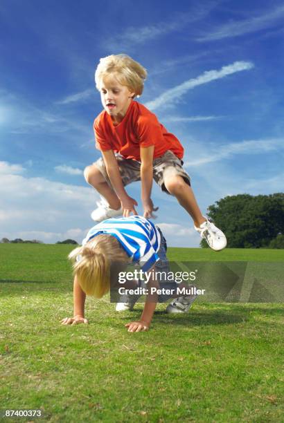 boy leapfrogging - bockspringen stock-fotos und bilder