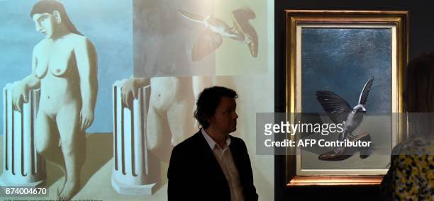 This combination photograph shows a woman looking at "God is not a Saint" by Belgium artist Rene Magritte which hides under its layers the missing...