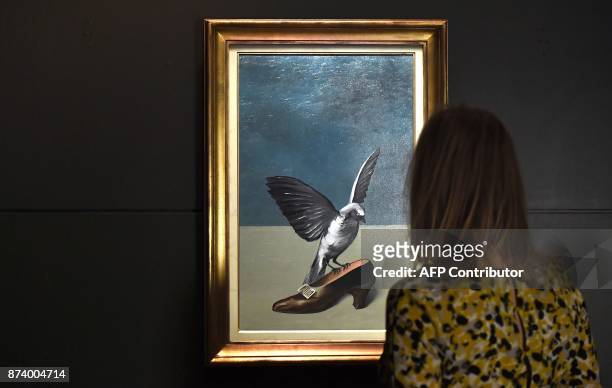 Woman looks at "God is not a Saint" by Belgium artist Rene Magritte which hides under its layers the missing and final piece of another Magritte's...