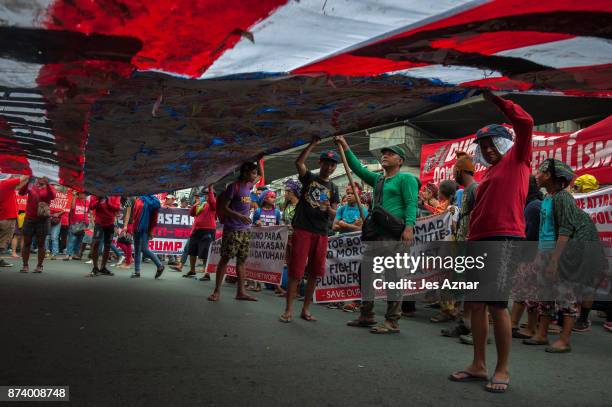 Protesters march on the streets and carry a US flag to burn as protest to US President Trump's visit in the Philippines on November 14, 2017 in...