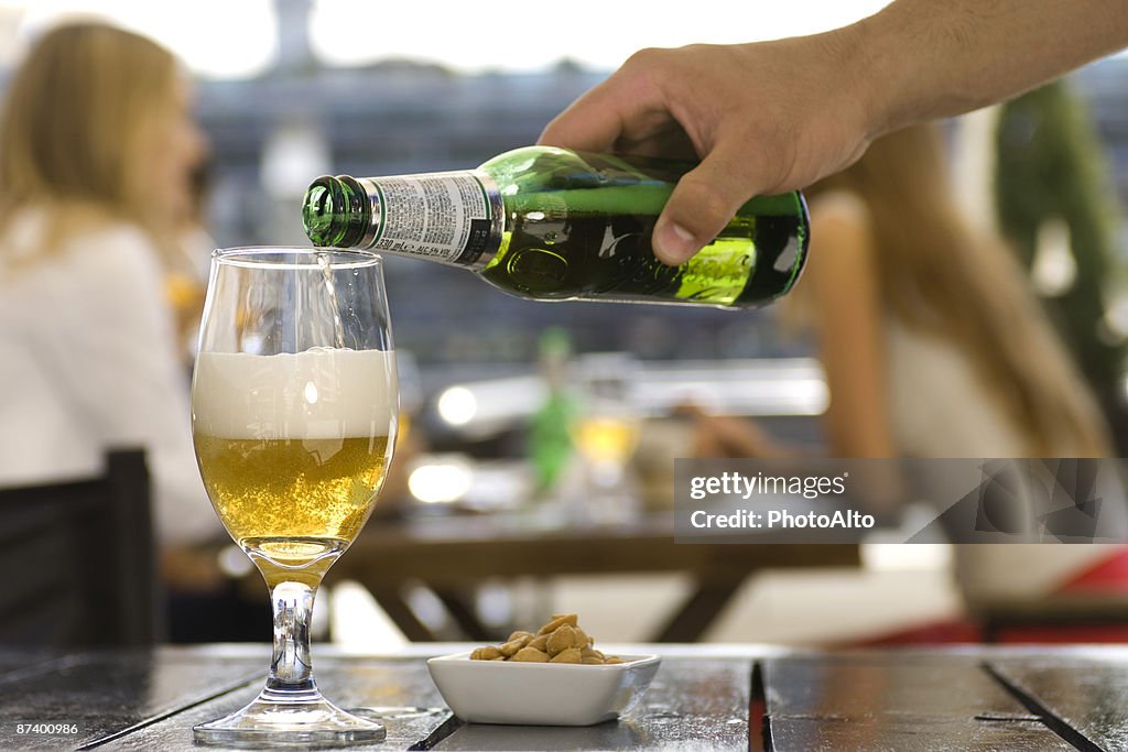 Pouring beer into glass at sidewalk cafe
