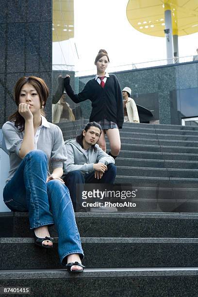 young friends relaxing on steps, low angle view - portrait of young woman standing against steps imagens e fotografias de stock