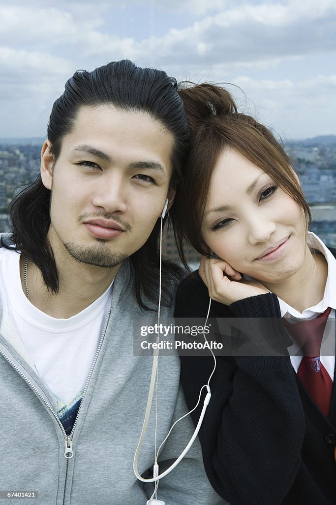 Young couple sharing earphones, smiling