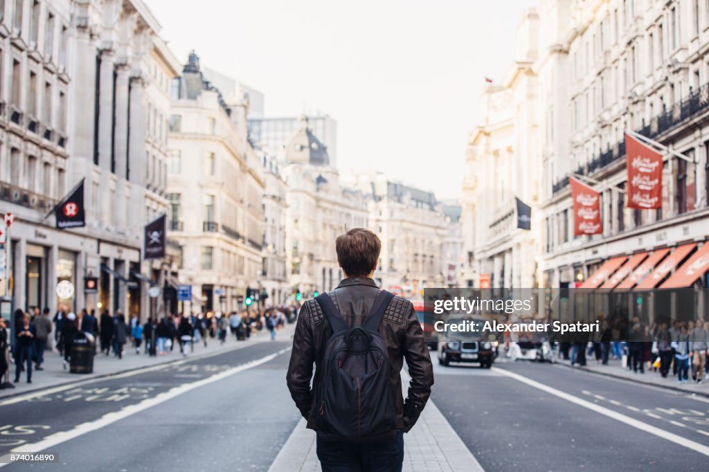 Tourist with backpack walking on Regent Street in London, UK