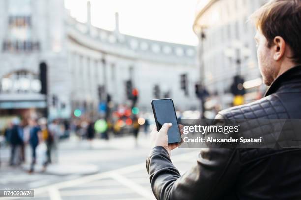 man checking his phone on the street, rear view - piccadilly fotografías e imágenes de stock