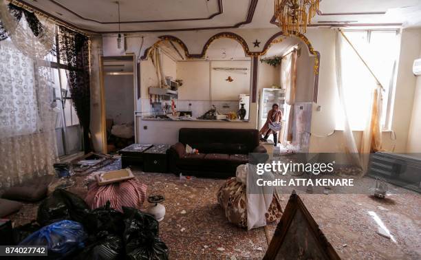 An Iranian woman collects items from an apartment in a damaged building in the town of Sarpol-e Zahab in the western Kermanshah province near the...