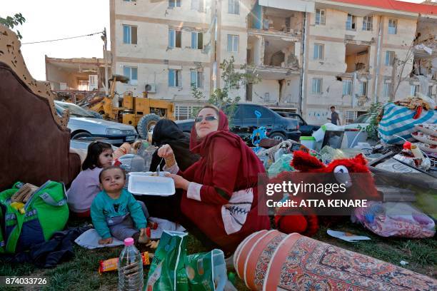 Iranians eat by salvaged belongings outside near damaged buildings in the town of Sarpol-e Zahab in the western Kermanshah province near the border...