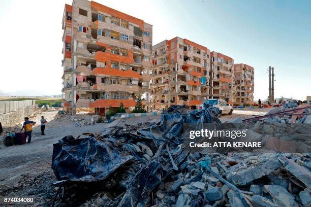 Picture taken on November 14, 2017 shows a view of a burnt vehicle and buildings damaged by a 7.3-magnitude earthquake that struck two days before in...