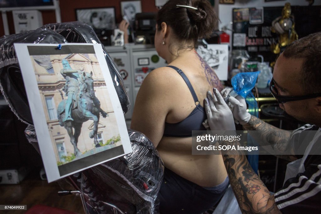 A girl sits on a chair during tattooing while the tattoo...
