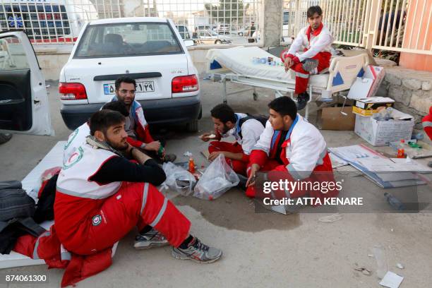 Iranian Red Crescent paramedics eat and rest during a break from tending to quake victims and survivors, in the town of Sarpol-e Zahab in the western...