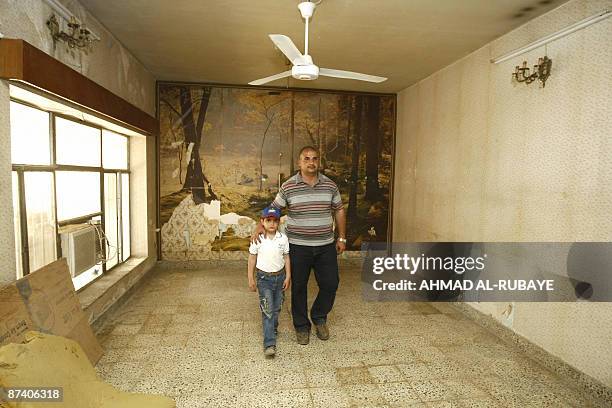 Duraid Malik and his son walk in a bare room of their home moments after it was handed back to them by the US and Iraqi army in the Yarmuk district...