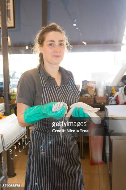 young female fishmonger holding filleted fish ready to pack for a customer. - filleted stock pictures, royalty-free photos & images