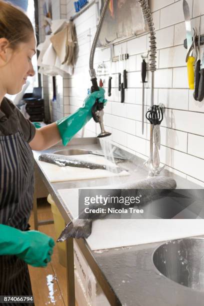 young female fishmonger washing and gutting a fish - knife splash stock-fotos und bilder