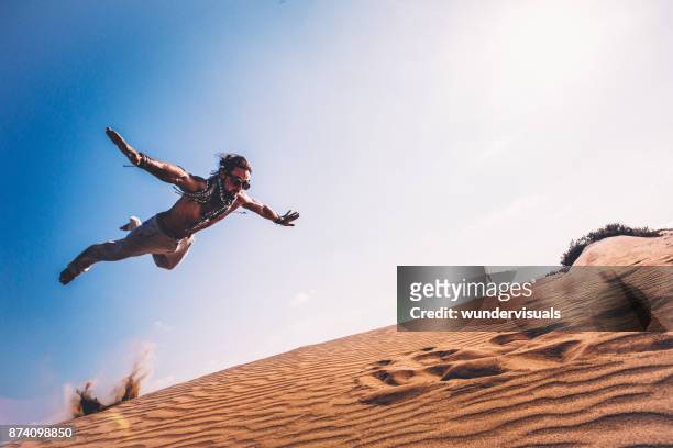 young man with retro glasses doing parkour jump in desert - male gymnast stock pictures, royalty-free photos & images