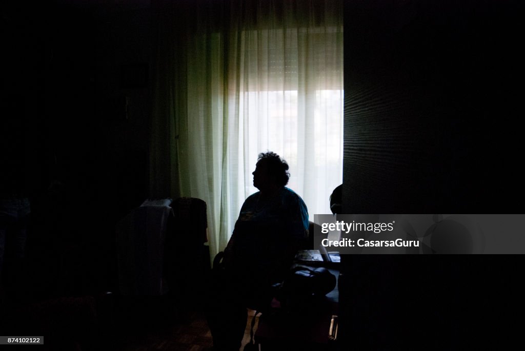 Senior Woman Alone in Dark Room