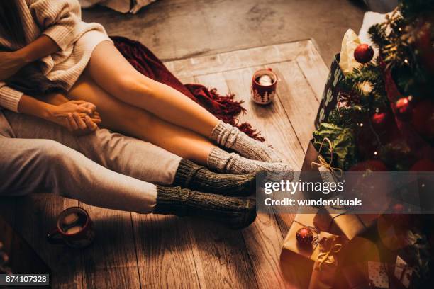 par de mãos dadas e relaxamento sentado sob a árvore de natal - atividade romântica - fotografias e filmes do acervo