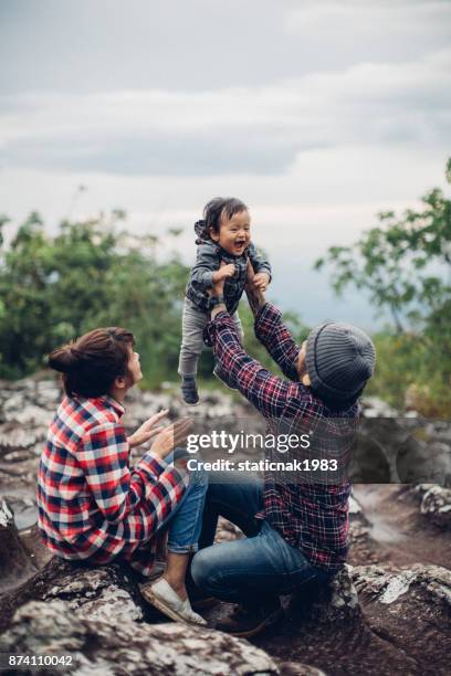ung familj och son sitta på sten i skogen på thailand. - bush baby bildbanksfoton och bilder