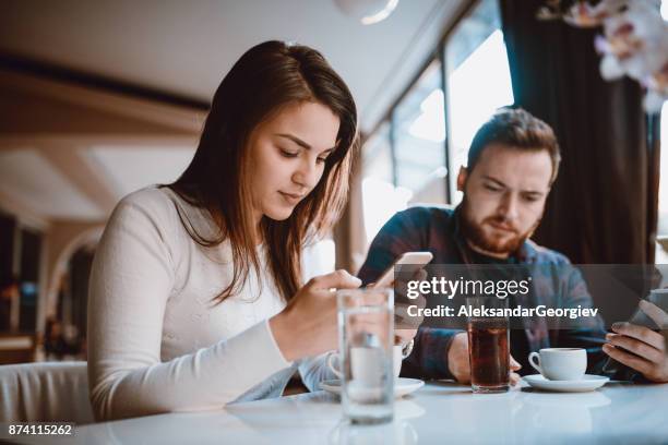 echtpaar met onbeleefd gedrag, kijken naar hun smartphone in een cafe - ignore stockfoto's en -beelden