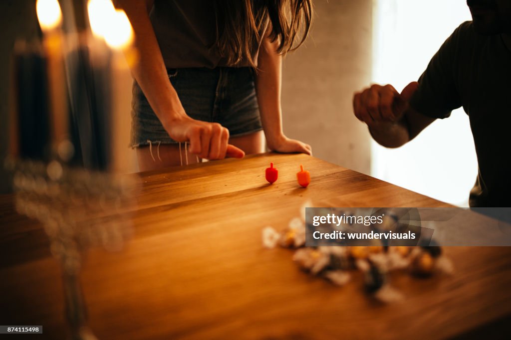 Man and woman with menorah playing dreidel game on Hannukah