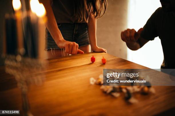 man and woman with menorah playing dreidel game on hannukah - dreidel stock pictures, royalty-free photos & images