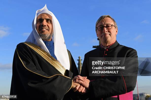 Secretary General of the Muslim World League Mohammed Al-Issa shakes hands with rector of the Notre-Dame de Paris Cathedral Patrick Chauvet as they...