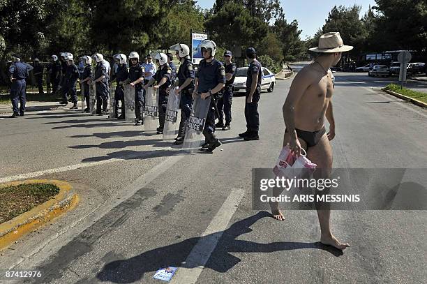 Bather passes in front of riot police during a protest of right-wing nationalist Popular Orthodox Rally members, near the meeting place for the...