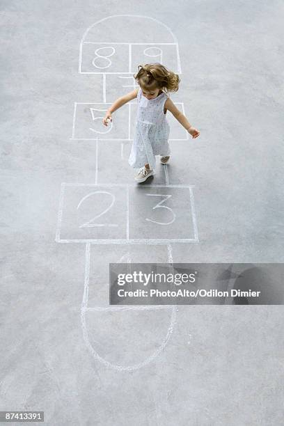 little girl playing hopscotch, high angle view - hopscotch stock-fotos und bilder