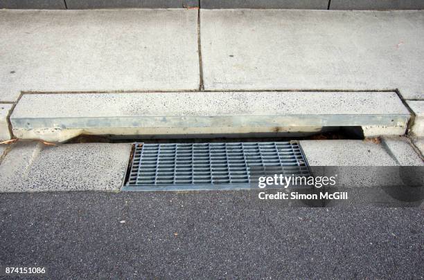 metal grate and concrete street drain on the sidewalk of a road - grille stock pictures, royalty-free photos & images