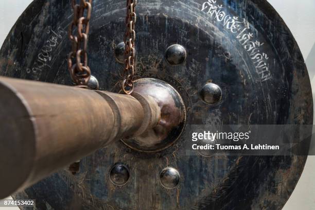 close-up of an old hanging steel gong and wooden mallet at the golden mount at wat saket in bangkok. - percussion mallet stockfoto's en -beelden