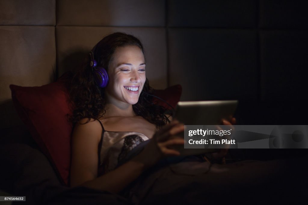 Young woman looking at digital tablet in bed