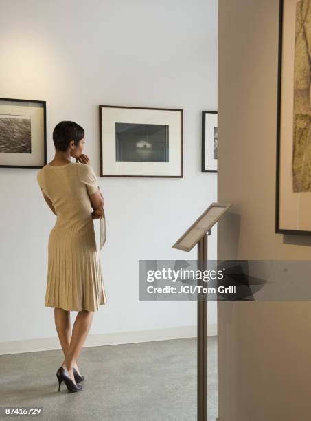 african woman enjoying photographs in museum - evening gowns stockfoto's en -beelden