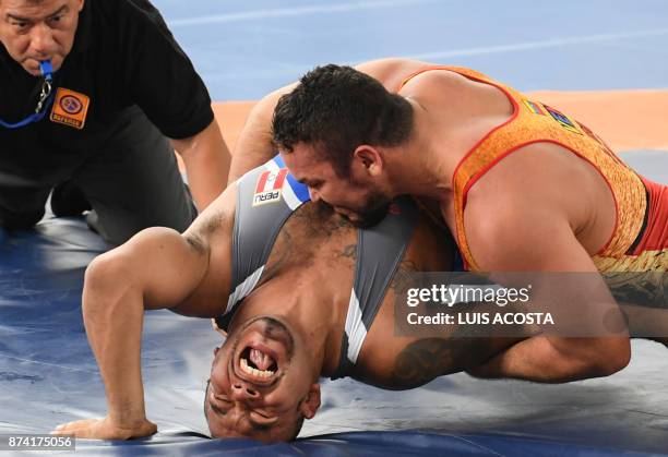 Venezuelan Jose Diaz wrestles with Peruvian Ronaldo Valverde in a men's 97 kg Greco-Roman wrestling bout during the XVIII Bolivarian Games in Santa...