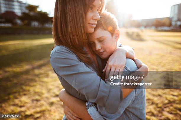 teenager mit mama tröstet ihren sohn umarmt - mama kind kuscheln stock-fotos und bilder