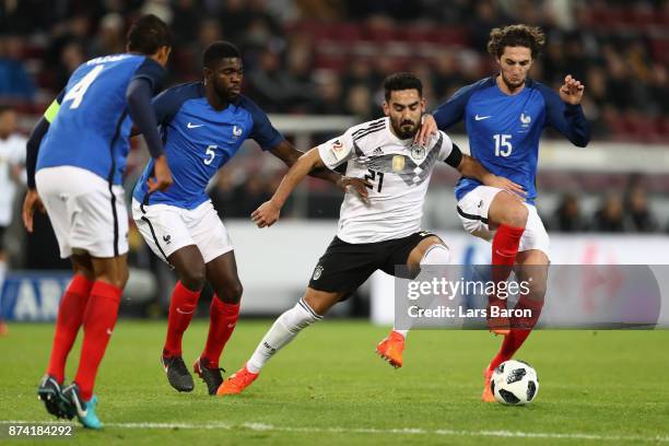 Samuel Umtiti of France and Adrien Rabiot of France battle for possession with IIkay Gundogan of Germany during the international friendly match...