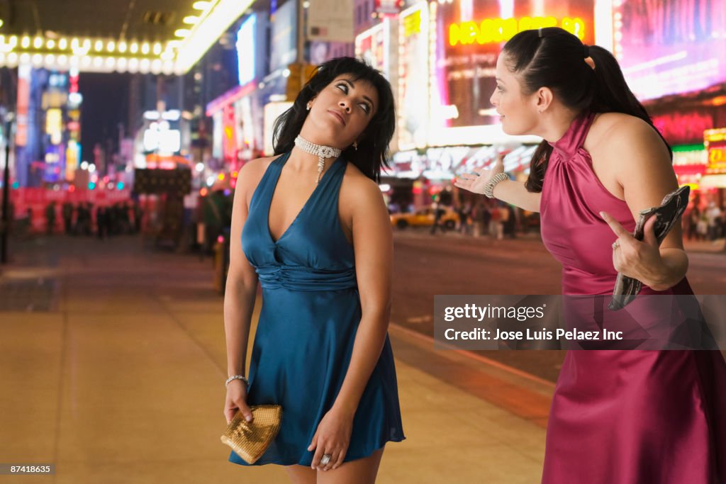 Hispanic friends arguing on sidewalk at night