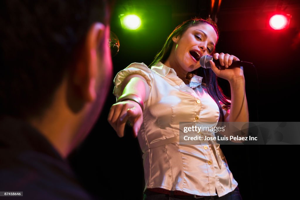 Hispanic woman singing in nightclub