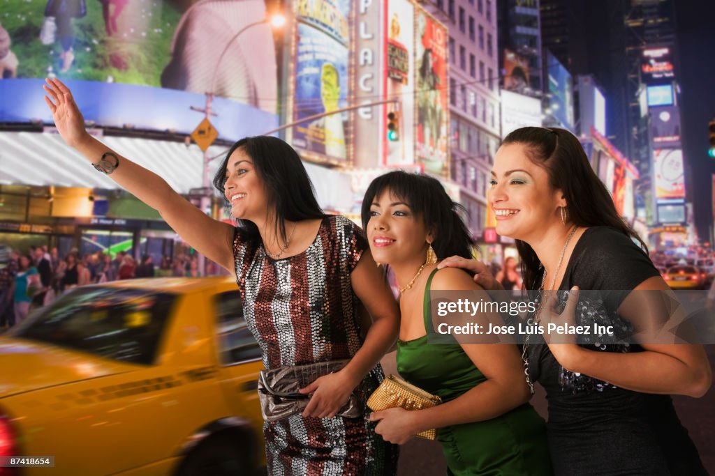 Hispanic friends hailing taxi cab