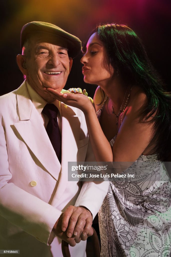 Hispanic woman kissing senior man in nightclub