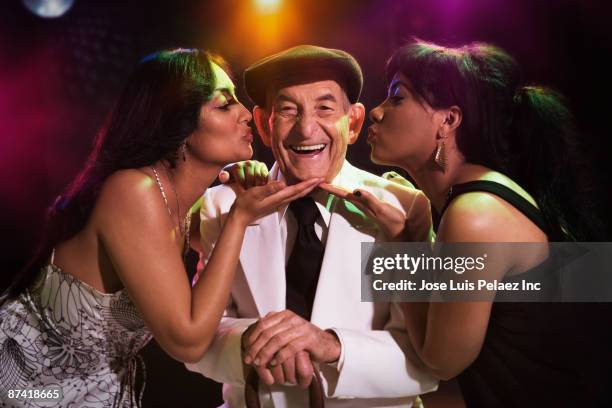 hispanic women kissing senior man in nightclub - stereotypically upper class stock pictures, royalty-free photos & images