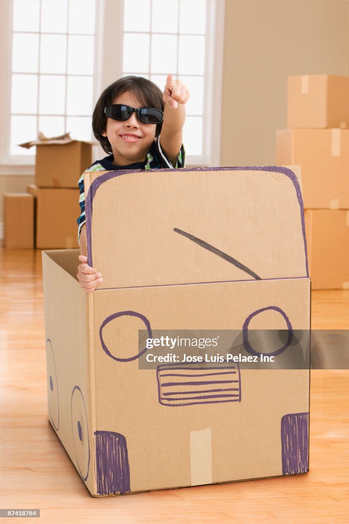 Hispanic boy driving cardboard bus