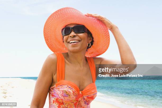 senior african woman in bathing suit on beach - cappello per il sole foto e immagini stock