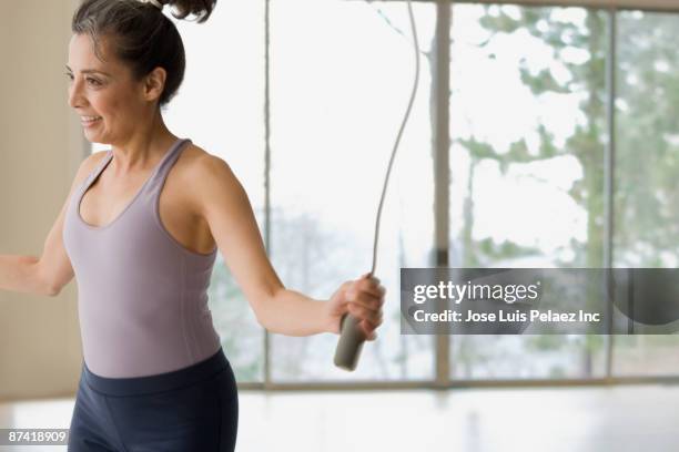 hispanic woman jumping rope during workout - springtouw stockfoto's en -beelden