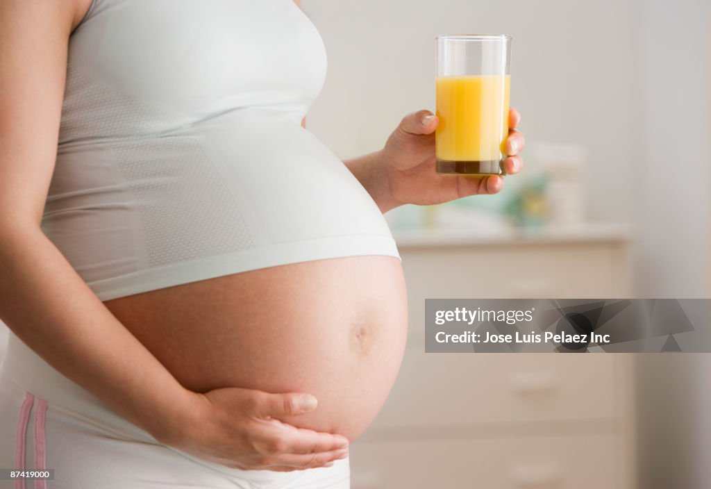 Pregnant Hispanic woman drinking orange juice
