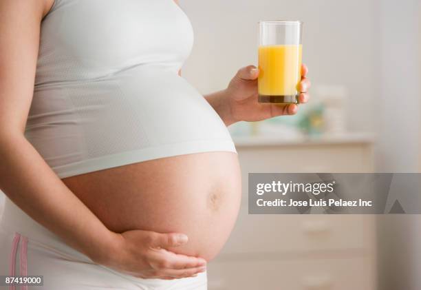 Pregnant Hispanic Woman Drinking Orange Juice, Foto de stock
